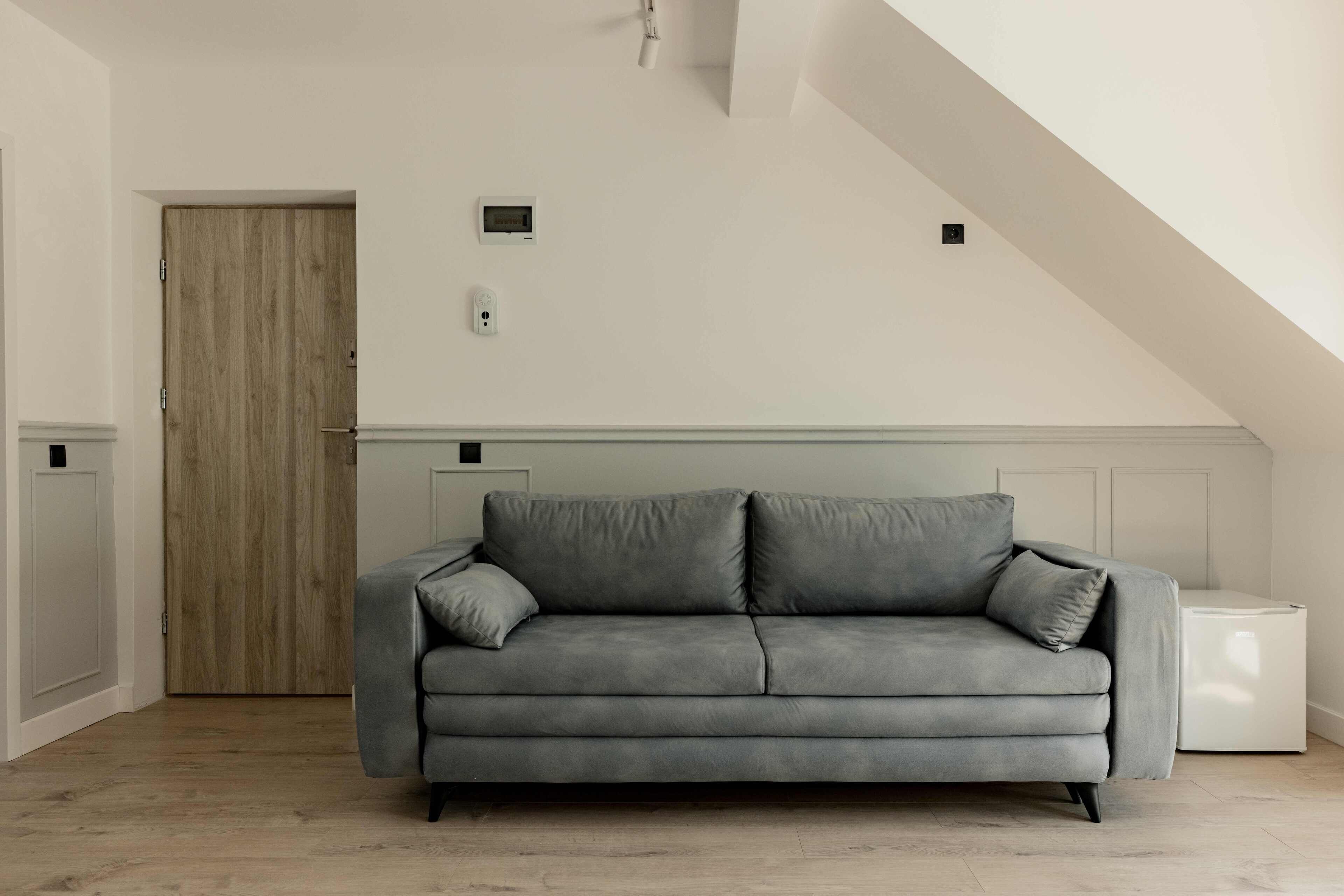 A modern living room with a grey sofa, a wooden door, and a white radiator.