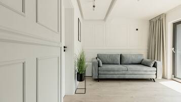 A modern living room with a grey sofa, a potted plant, and a sliding glass door.
