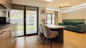 A modern kitchen with a dining area, a green sofa, and a view of the outdoors. - Nest Inn Meteor (Cluj-Napoca)