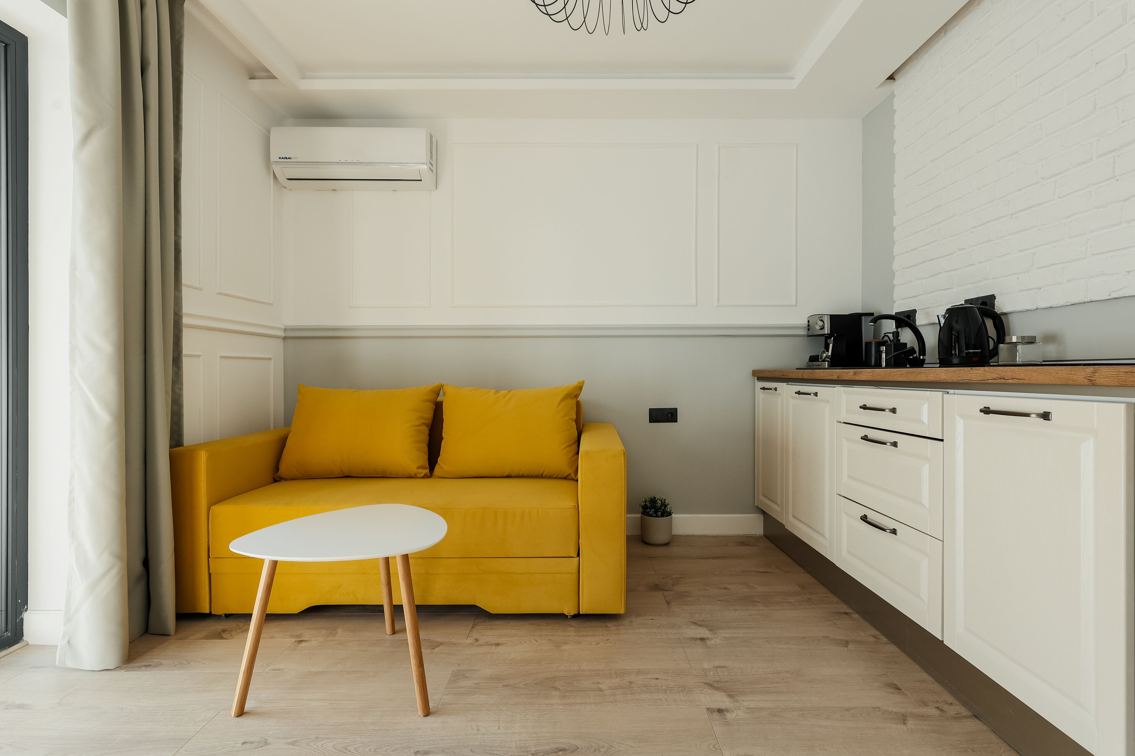 A modern living room with a yellow sofa, a white coffee table, and white cabinetry.