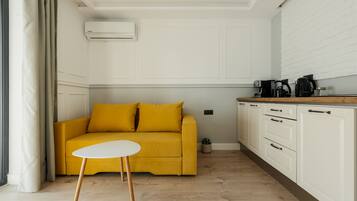 A modern living room with a yellow sofa, a white coffee table, and white cabinetry.