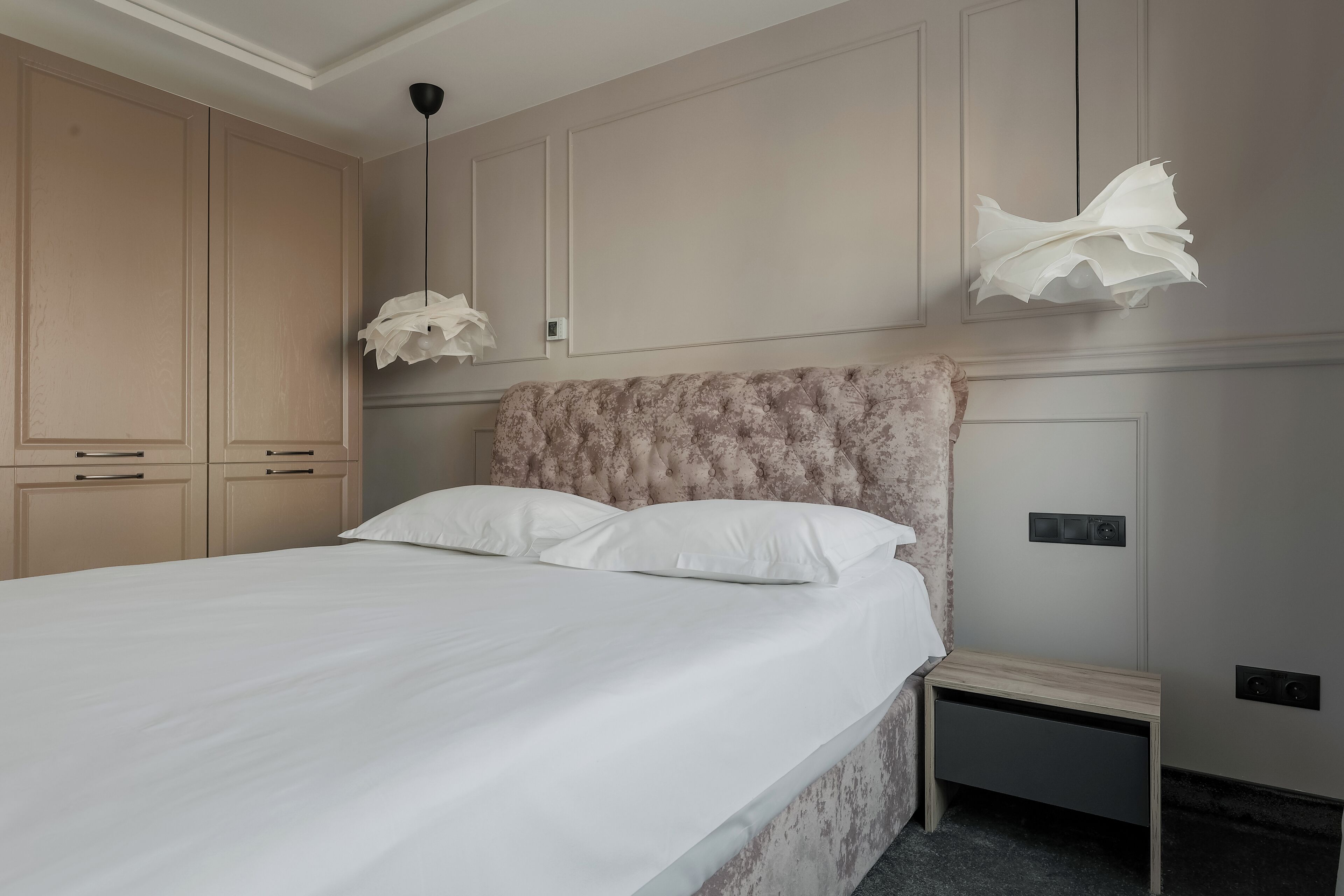 A bedroom with a large bed, a nightstand, and a wardrobe.