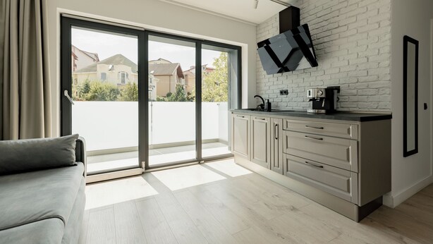 A modern kitchen with a large window, sliding glass door, and a white brick wall. - Nest Inn Meteor (Cluj-Napoca)