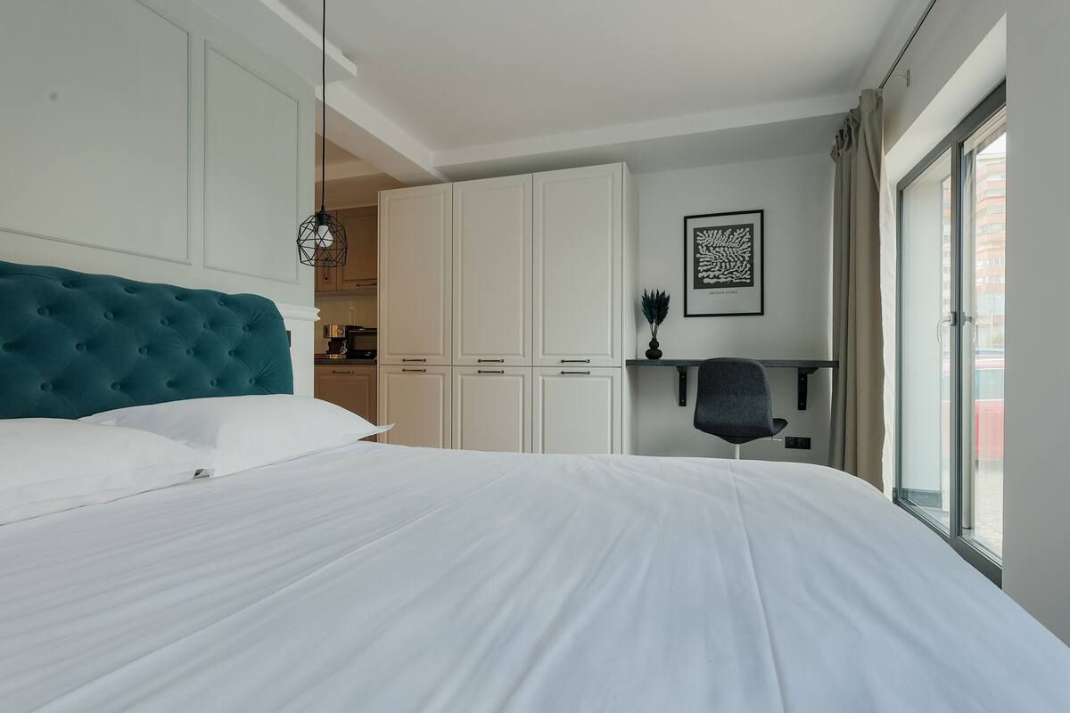 A hotel room with a large bed, a wardrobe, a desk, and a window.