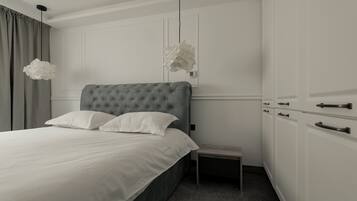 A neatly arranged bedroom with a tufted headboard bed, a bedside table, and a wardrobe with a handle.