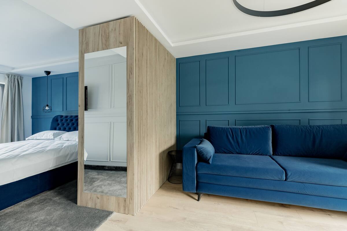 A modern bedroom with a bed, a blue sofa, and a wooden partition.