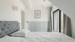 A bedroom with a tufted headboard, a framed artwork on the wall, and a window with curtains. - Nest Inn Meteor (Cluj-Napoca)