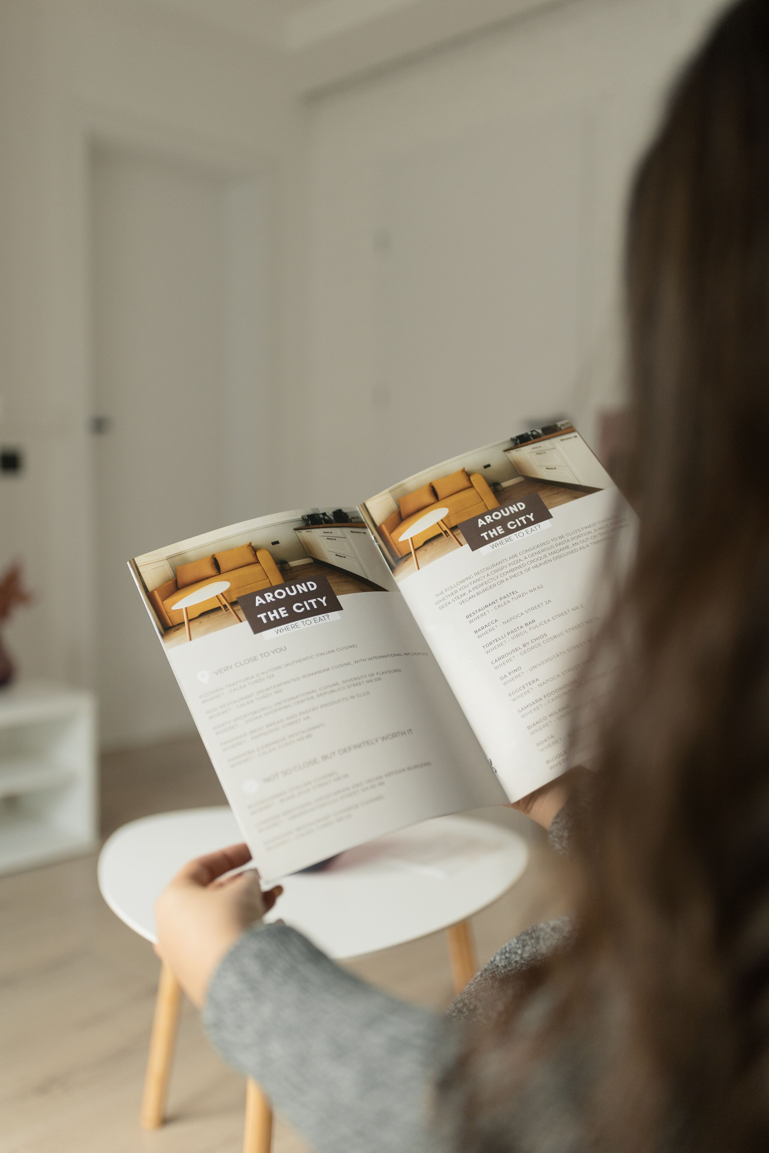 A person reading a brochure titled "Around the City" with a list of attractions and addresses.