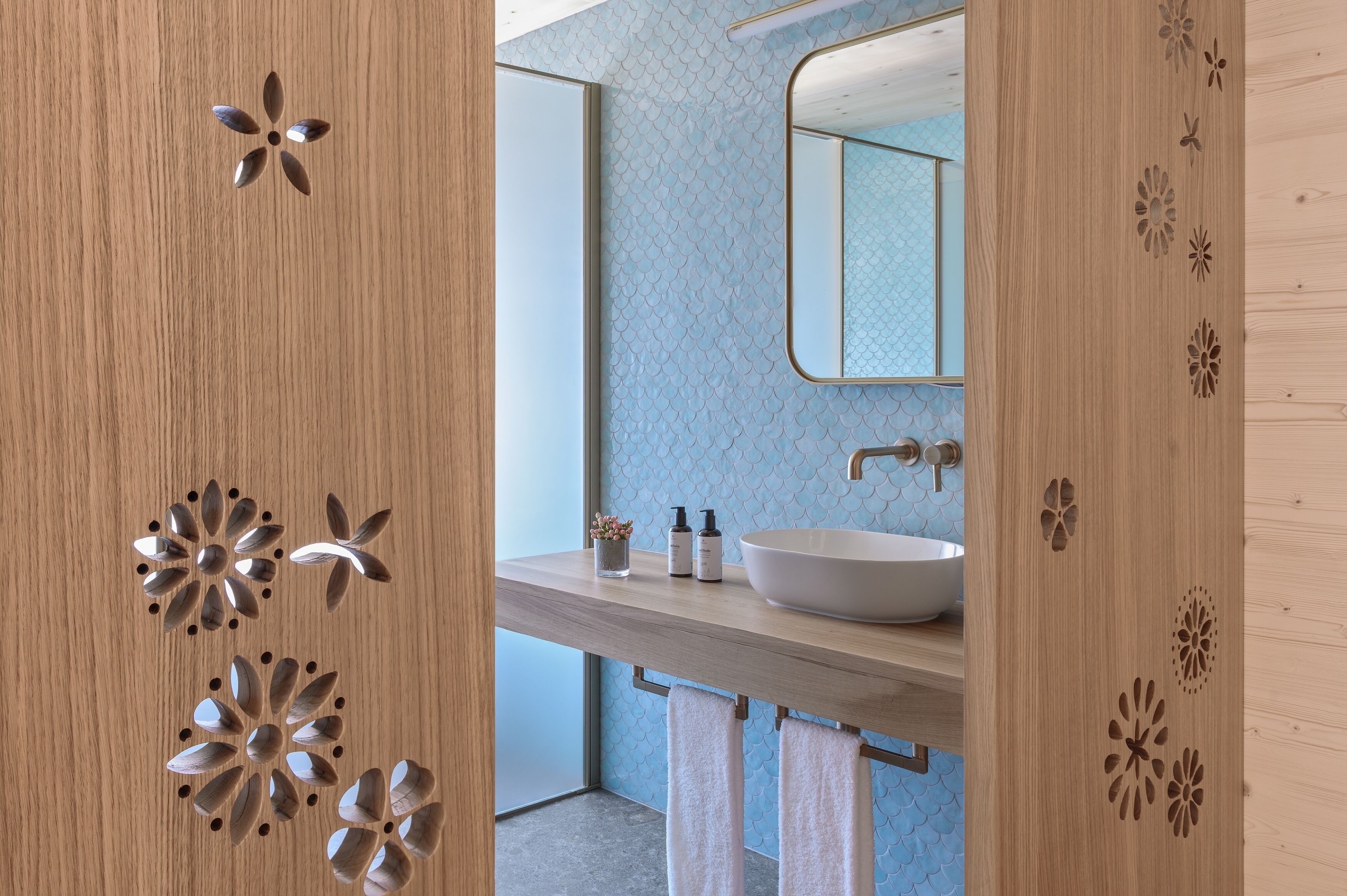 Un baño moderno con tocador de madera, un espejo grande y un lavamanos blanco.