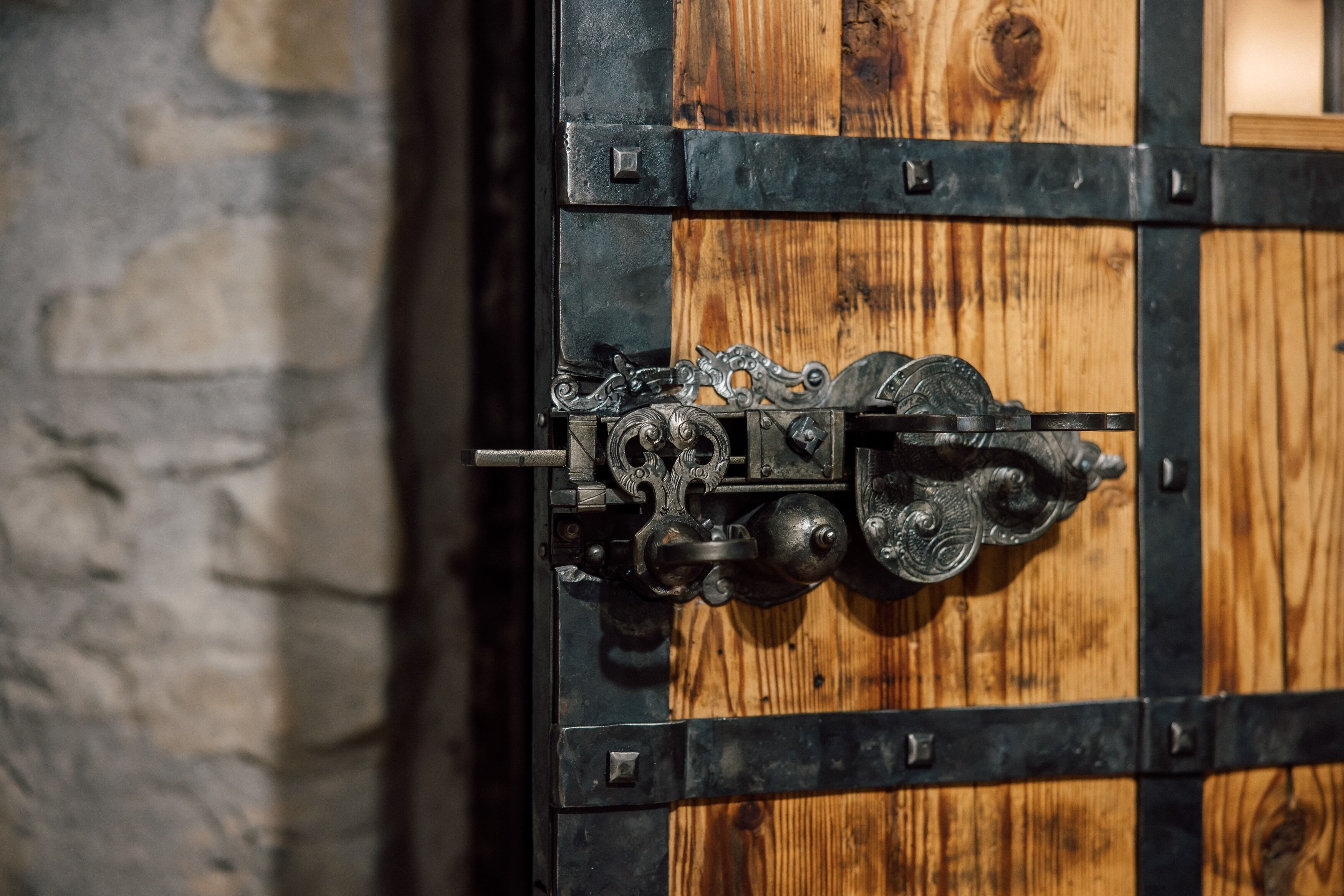 A close-up of a wooden door with metal hinges and a latch.