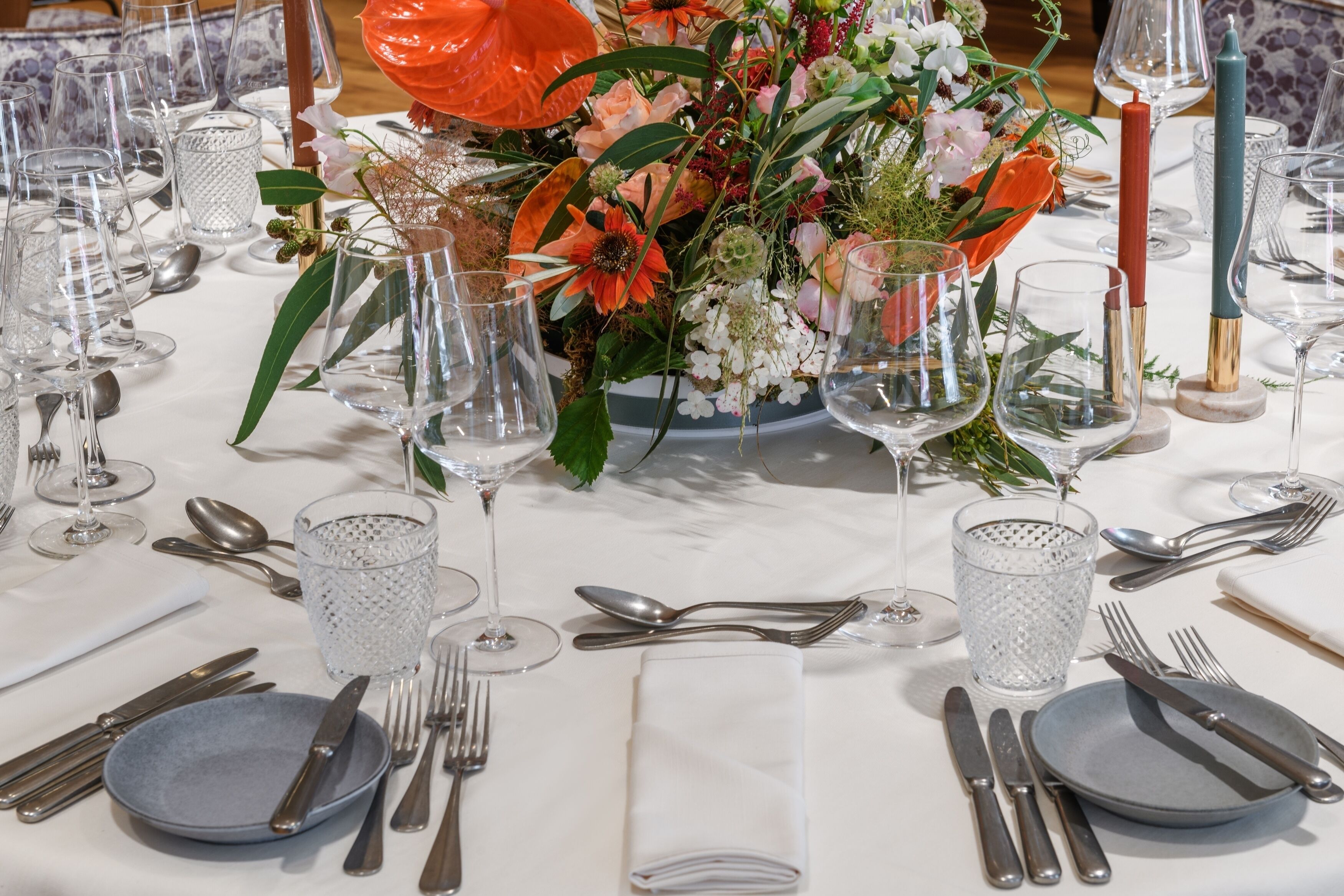 A table set for a formal dinner with clear glassware, silverware, and a centerpiece of flowers.