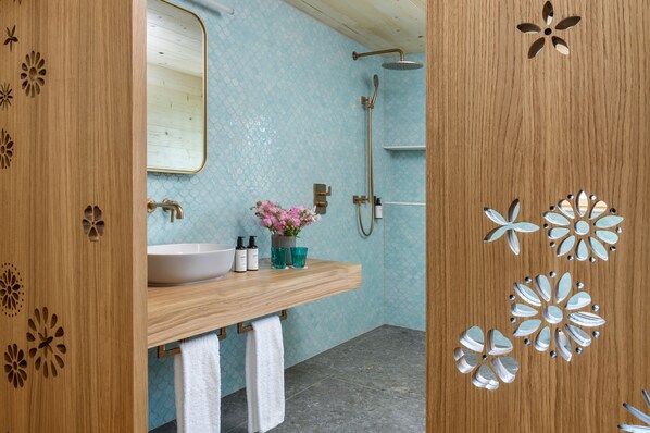 A bathroom with a wooden vanity, a sink, a mirror, and a shower.