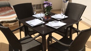 A dining table with four chairs, a vase with flowers, and a water dispenser on the wall. - 1 BED APARTMENT IN THE HEART OF LAS AMERICAS, POOL & WI-FI (Playa Delas Americas)