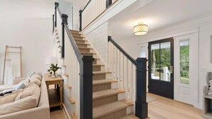 Un escalier avec un luminaire, une porte donnant sur l’extérieur et un canapé au premier plan.