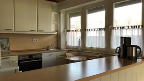 A kitchen with a wooden countertop, a sink, a stove, and a coffee maker. - Vacation home directly on the dike Pet friendly (Wurster Nordseeküste)