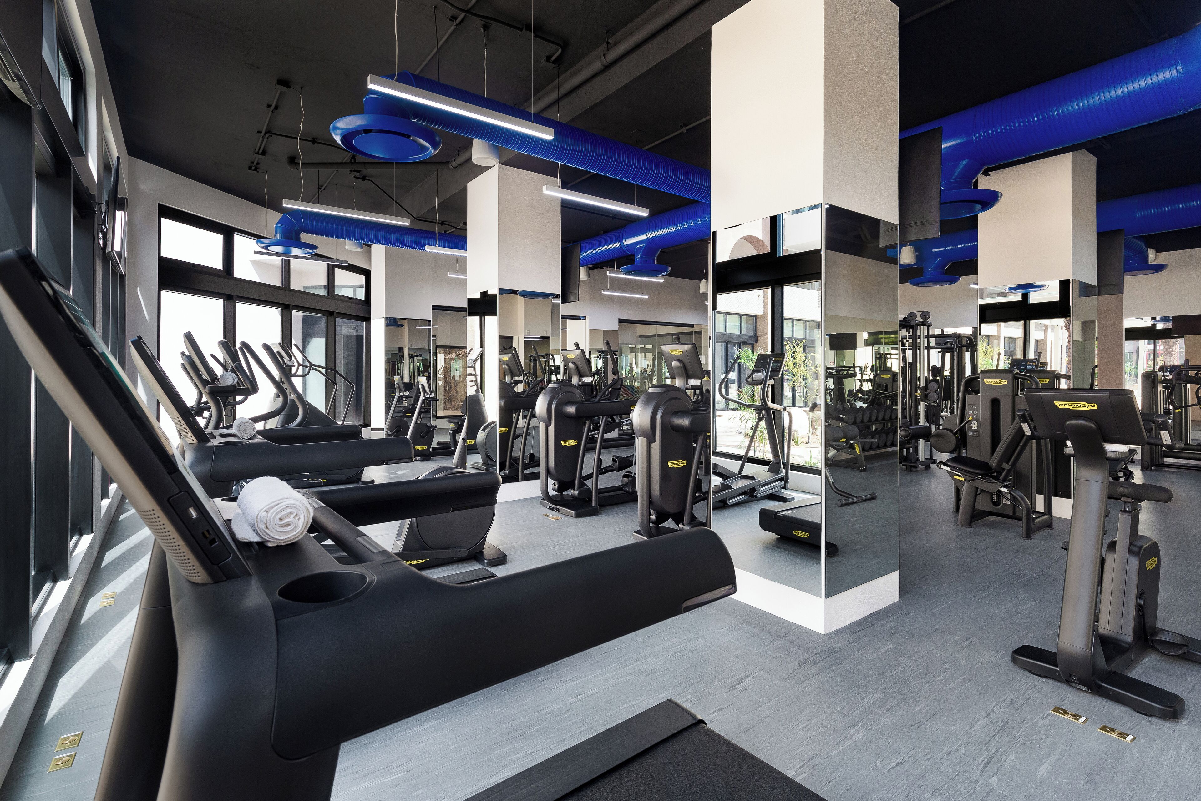 Una palestra moderna con tapis roulant, macchinari per pesi e specchi.
