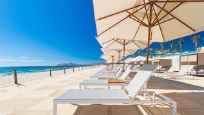 A beachside hotel with sun loungers under large umbrellas, a sandy beach, and a clear blue sky. - Villa La Valencia Los Cabos Beach Resort & Spa - All Inclusive (San José del Cabo)