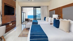 Una habitación de hotel con dos camas, televisión, ventilador de techo y vista al mar.