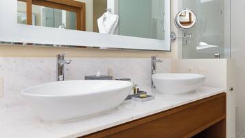 A modern bathroom with two large white sinks, a large mirror, and a wooden vanity.
