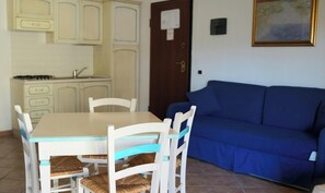 Un coin repas avec une table et des chaises, une cuisine équipée de placards et un canapé bleu.