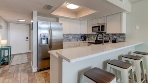 A modern kitchen with a central island, stainless steel appliances, and a microwave.