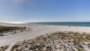 A wide sandy beach with a clear sky and calm sea.