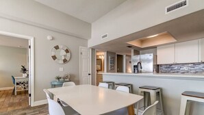 A modern kitchen with white cabinets, a stainless steel refrigerator, and a tiled backsplash.