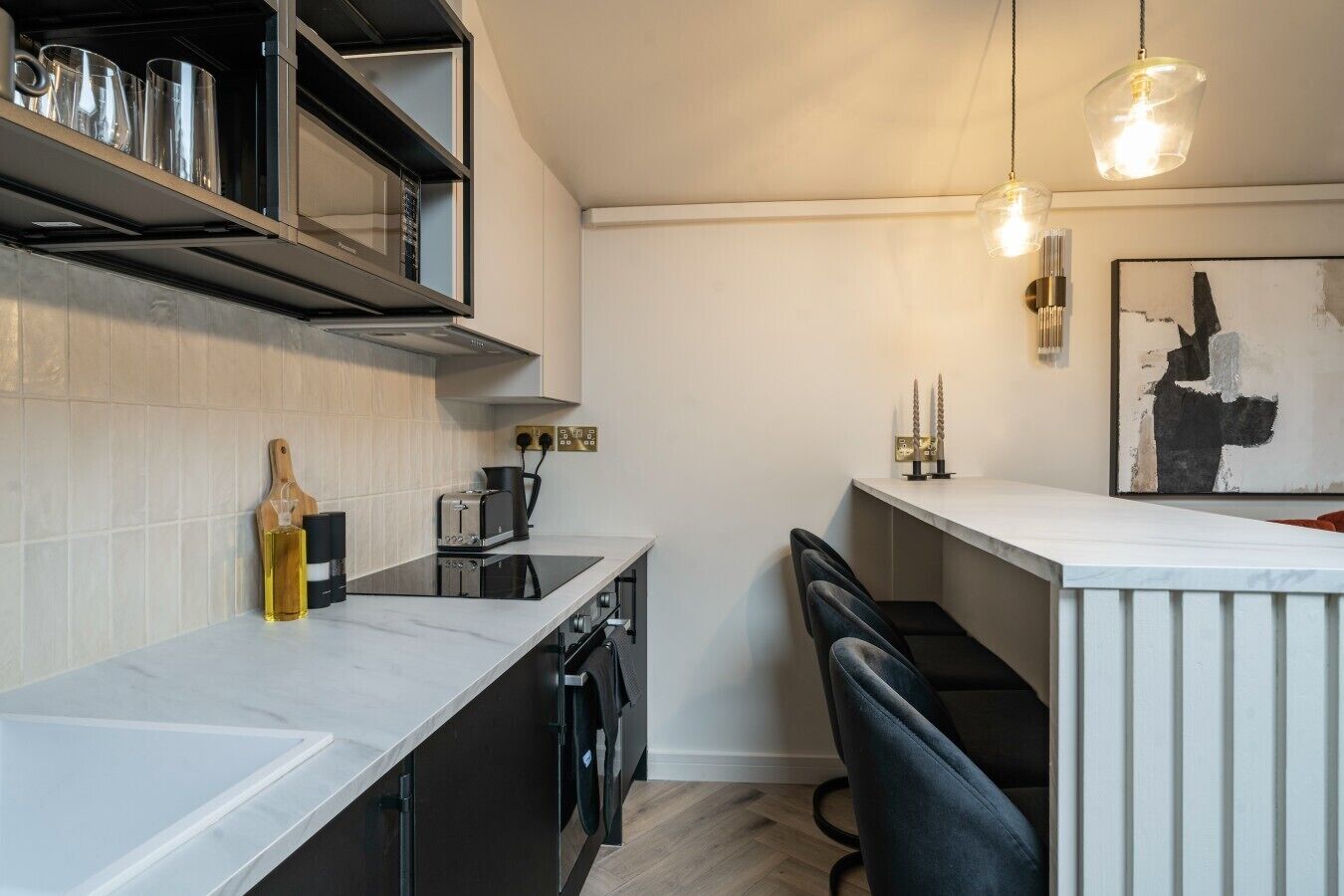 A modern kitchen with a built-in microwave, a coffee maker, and a wine bottle on the counter.