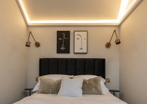 A neatly made bed with a black headboard, two bedside tables, and wall-mounted lamps. - 🌿 Countryside Escape – Chic Tiny Home in the Heart of the Cotswolds (Blockley)