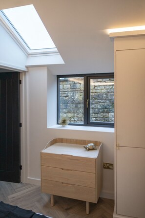 A room with a skylight, a window with a stone wall view, a wooden dresser, and a door. - 🌿 Countryside Escape – Chic Tiny Home in the Heart of the Cotswolds (Blockley)