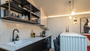 A modern kitchen with a central island, black cabinetry, and a white countertop. - Chic Cotswold Tiny Home - Oddity House (Blockley)