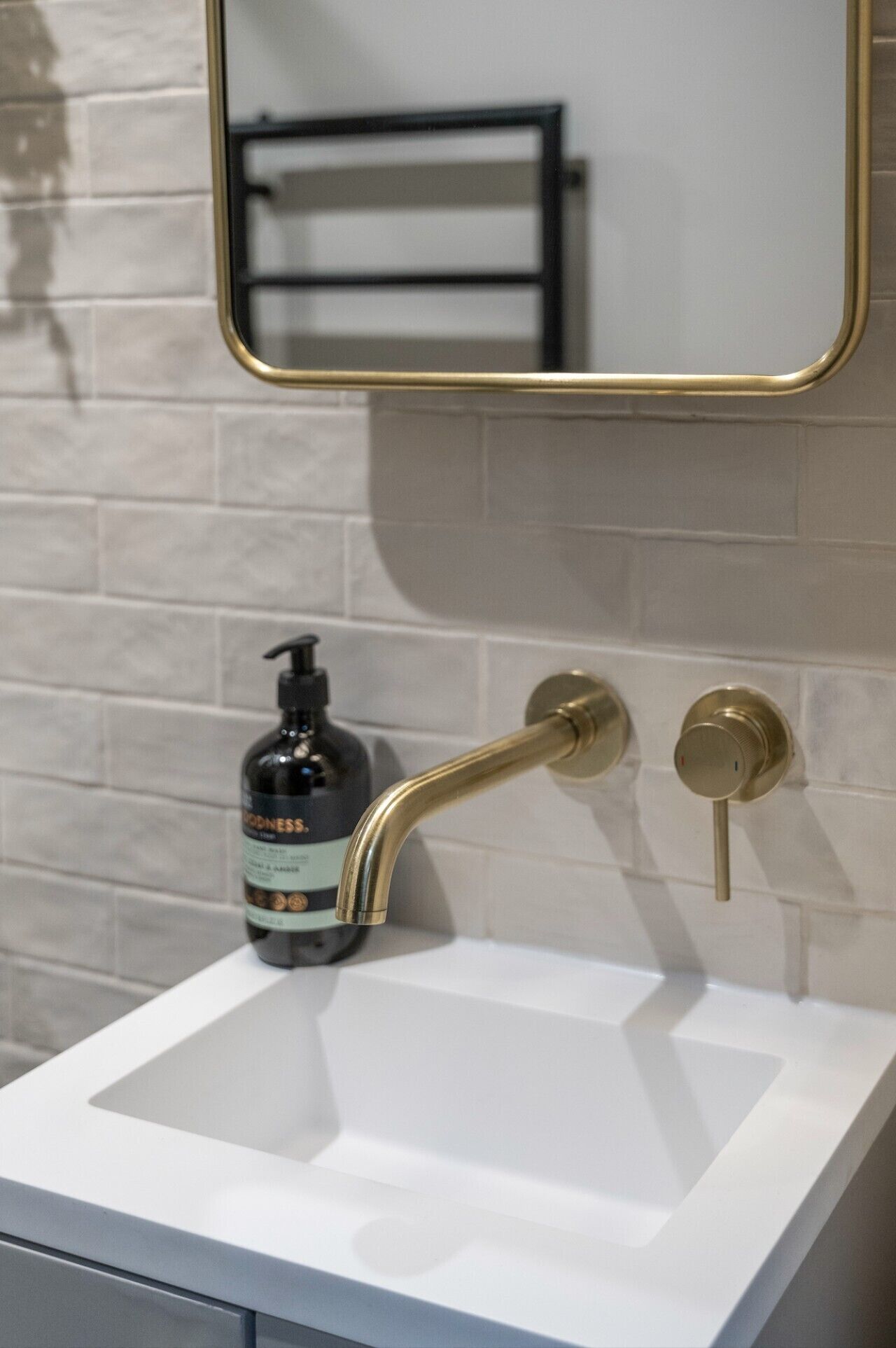 A bathroom with a white sink, a gold faucet, and a mirror with a gold frame.