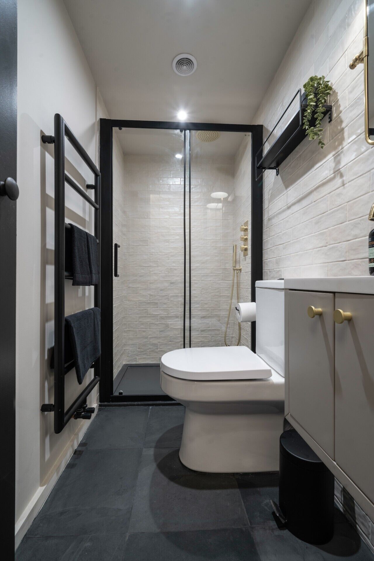 A modern bathroom with a shower, toilet, and a towel rack.