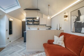 A modern kitchen with a central island, pendant lighting, and a contemporary art piece on the wall.