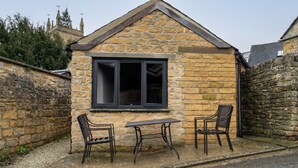 A stone building with a pitched roof, a window, and two chairs. - 🌿 Countryside Escape – Chic Tiny Home in the Heart of the Cotswolds (Blockley)