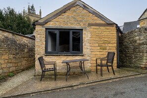 A stone building with a pitched roof, a window, and two chairs. - 🌿 Countryside Escape – Chic Tiny Home in the Heart of the Cotswolds (Blockley)