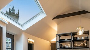 A modern kitchen with a skylight, a built-in shelf, and a wooden floor. - Chic Cotswold Tiny Home - Oddity House (Blockley)