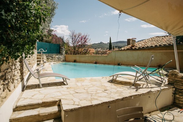 A stone pool with lounge chairs, a stone wall, and a view of a village in the background. - Villa Balleti - private pool with a view (Apt)