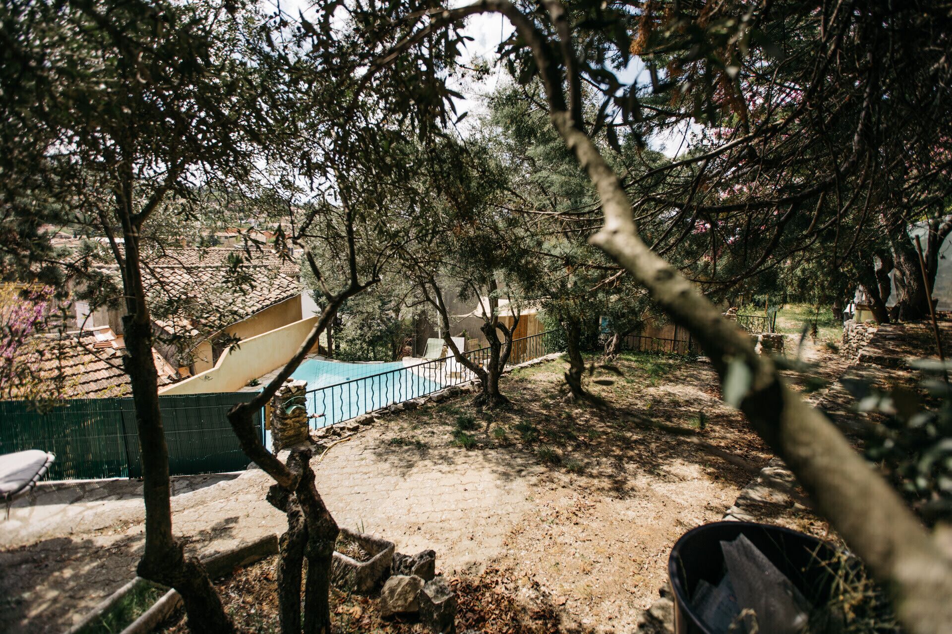 Um pátio com piscina, cercado por árvores e um muro de pedra.