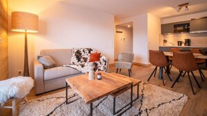 Un salon moderne comprenant un canapé, une table basse et un coin repas avec des chaises.