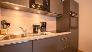 Une cuisine moderne équipée d’un évier en acier inoxydable, d’une machine à café et d’un four à micro-ondes.
