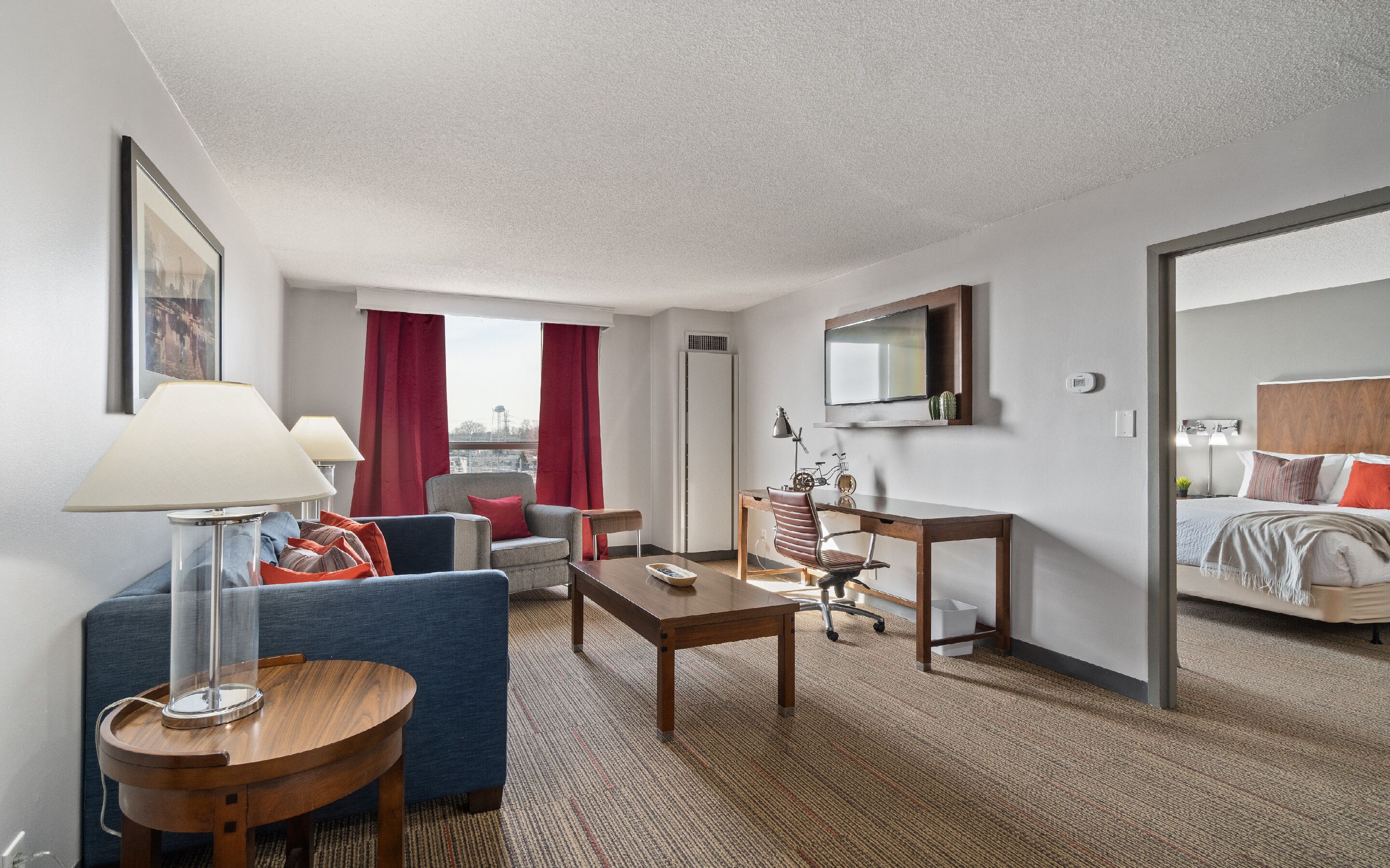 Une chambre d’hôtel avec un canapé, un fauteuil, un bureau et un lit.
