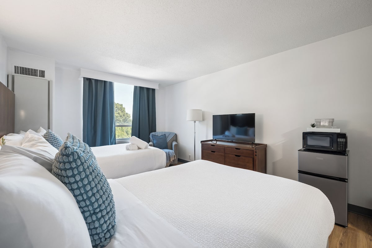 A hotel room with two beds, a television, a microwave, and a small refrigerator.