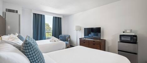 A hotel room with two beds, a television, a microwave, and a small refrigerator.