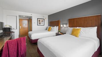A hotel room with two beds, a desk with a computer, a chair, and a TV.