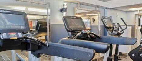 A gym with treadmills, stationary bikes, and a rowing machine.