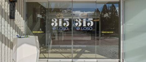Entrada de um edifício moderno com portas de vidro exibindo o número 315 e o texto "LOSO".