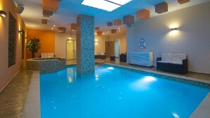 Ein Innenpool mit gefliestem Boden, einer zentralen Säule und einer Decke mit eingelassener Beleuchtung.
