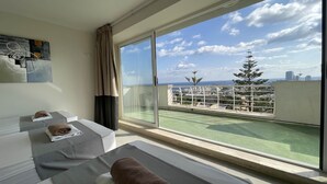 Ein Hotelzimmer mit einer großen Schiebeglastür, die auf einen Balkon mit Blick auf die Stadt führt.