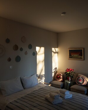 A hotel room with a bed, a chair, a small table with a plant, and a painting on the wall. - Stagiates Guest House Room 3 (Volos)